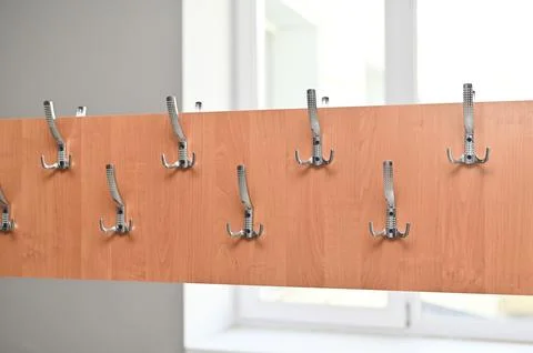 Wall-mounted coat rack with multiple metal hooks on wooden panel, Stock Photos
