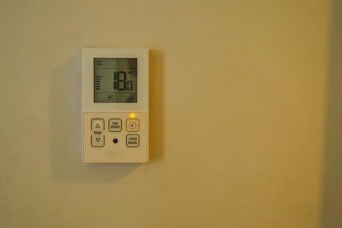 Wall mounted digital aircon remote control panel showing temperature indicato Stock Photos