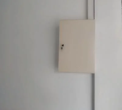 Wall-Mounted Electrical Fuse Box Cover on White Interior Wall Stock Photos