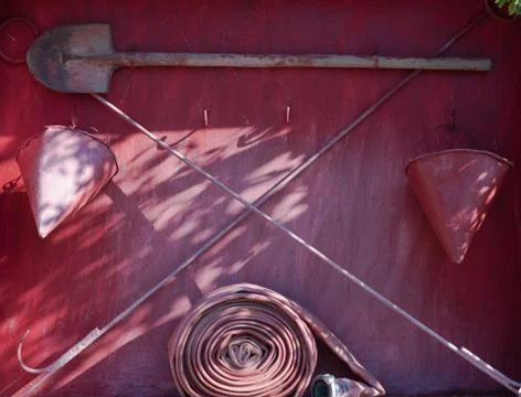 Wall-mounted fire shield with fire-fighting tools. Shovel, hook , axe, cone b Stock Photos