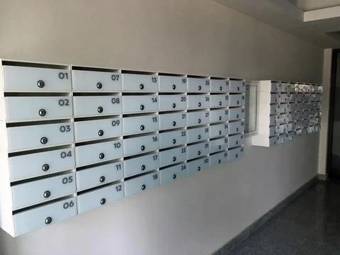 Wall Mounted Grid of Numbered Mailboxes in Indoor Hallway Stock Photos