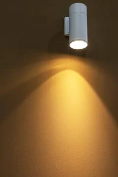 A wall-mounted light bulb illuminates the walls of the room. Stock Photos