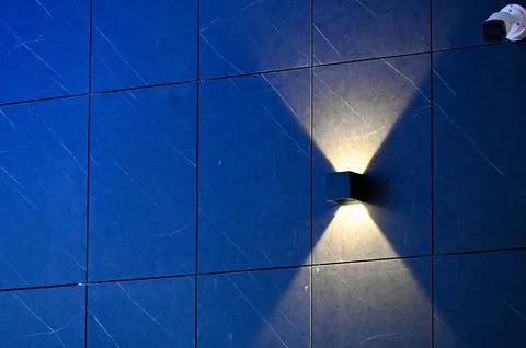 Wall-mounted light fixture illuminates modern indoor building with clean blue Stock Photos