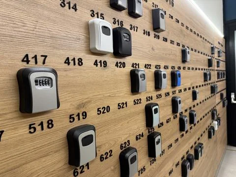 Wall-mounted lockboxes with codes organized in rows on wooden panel with nu.. Stock Photos