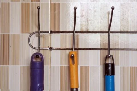 Wall-mounted metal rack with hooks holding cleaning tools like brooms and m.. Stock Photos