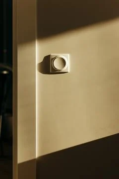 Wall mounted modern light switch with round button in home interior near doorway Stock Photos
