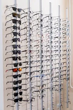 Wall-mounted optical display rack holding various eyeglasses frames and Stockfoto's
