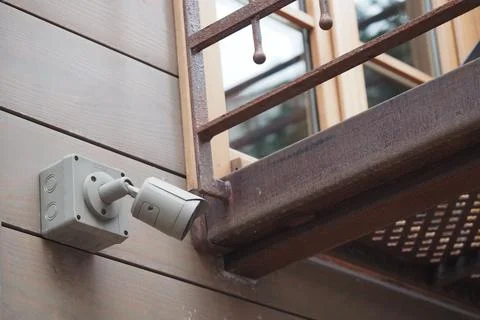 Wall-mounted security camera near wooden balcony Stock Photos