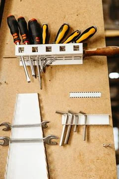 Wall-mounted tool organizer with various hand tools in a metal workshop Stock Photos