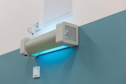 Wall-mounted UV sterilization lamp emitting blue light for disinfection in a Stock Photos