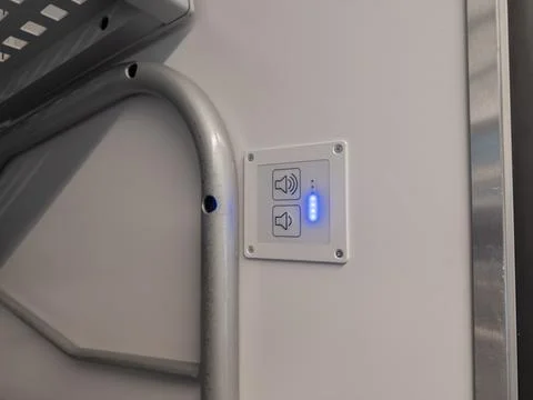A wall-mounted volume control panel featuring illuminated blue indicator lights Stock Photos