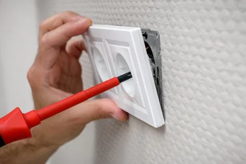Wall mounting outlet using screwdriver, electrician hand close-up. Foto stock