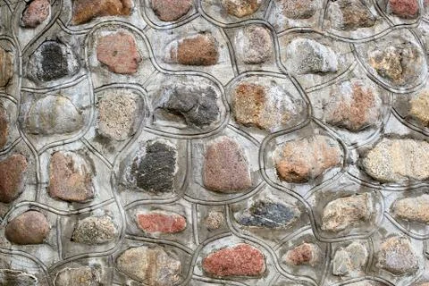Wall of multi-colored round stone fastened with concrete Stock Photos