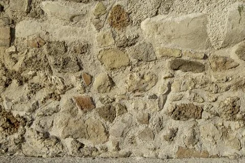 Wall of an old building made of various rough stones and clay as a background Stock Photos