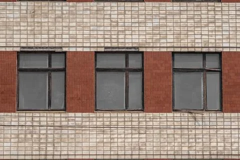 The wall of an old Soviet house, lined with ceramic tiles with large windows. Stock-Fotos