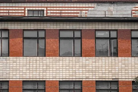 The wall of an old Soviet house, lined with ceramic tiles with large windows. Stock Photos
