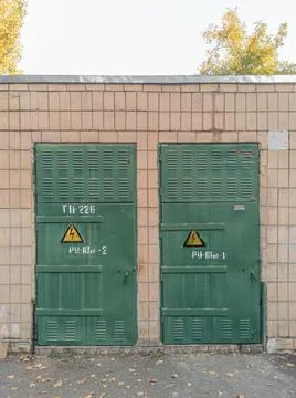 Wall of an old Soviet step-down electrical substation with a green door. Stock Photos