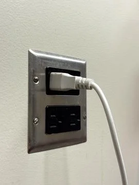Wall outlet with a white charging cable connected in a room during the day 写真素材