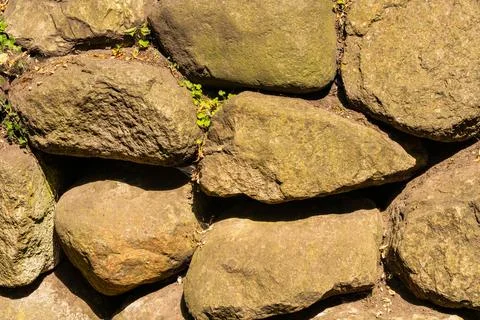 Wall paved with large cobblestones under harsh sunlight. Stock Photos
