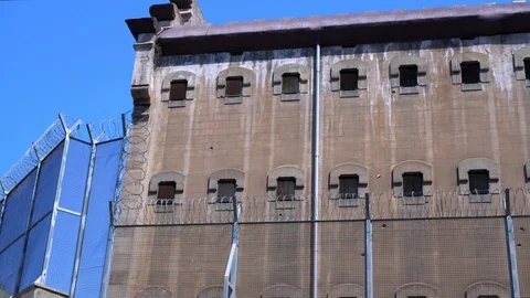 Wall of a prison building behind a barbed wire fence. Vídeos de archivo 115156406