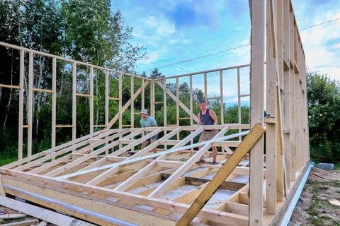 Wall raising shows two builders manually lifting completed wall frame into .. Stock Photos