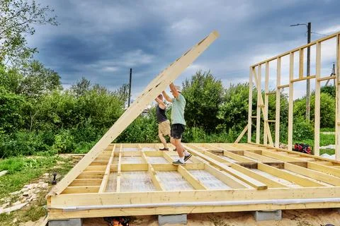Wall raising by two builders manually lifting completed wall frame into ver.. Stock Photos