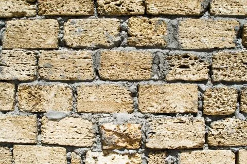 Wall from a rough yellow brick. background Stock Photos