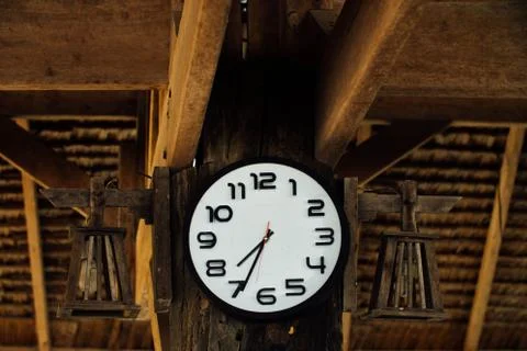 Wall round clock with white dial hanging on wooden wall. Clocks indicate time Stock Photos