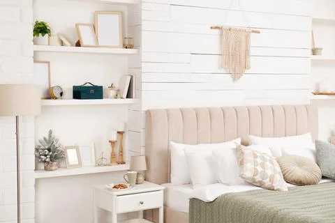 Wall shelves with beautiful decor elements in stylish bedroom interior Stock Photos