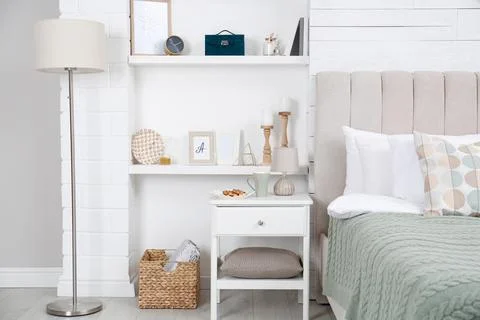 Wall shelves with beautiful decor elements in stylish bedroom interior Stock Photos
