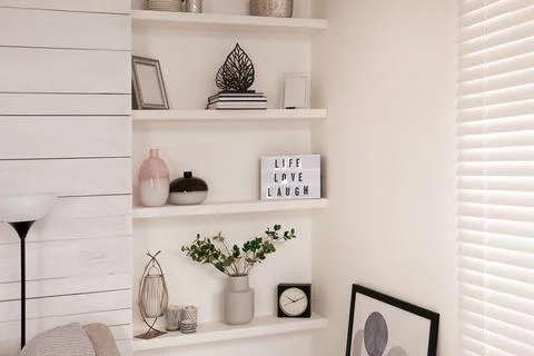 Wall shelves with beautiful decor elements indoors. Interior design Stock Photos