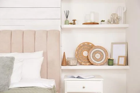 Wall shelves with beautiful decor elements in stylish bedroom interior Stock Photos