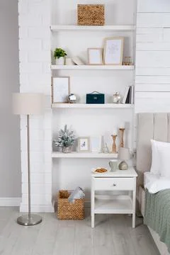 Wall shelves with beautiful decor elements in stylish bedroom interior Stock Photos