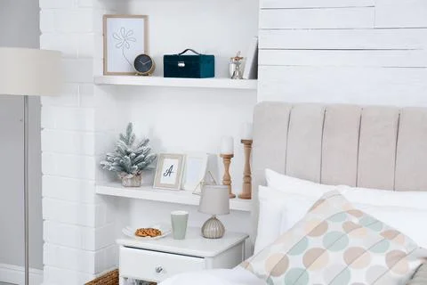 Wall shelves with beautiful decor elements in stylish bedroom interior Stock Photos
