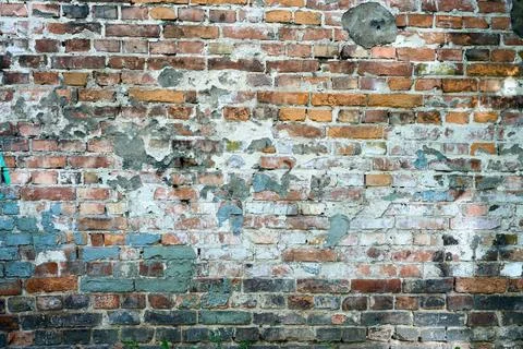 The wall shows different shades of brick and paint. It is located in a city a Stock Photos