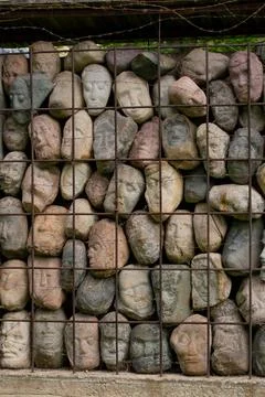 A wall of stones in the shape of human faces Stock Photos