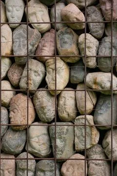 A wall of stones in the shape of human faces Stock Photos