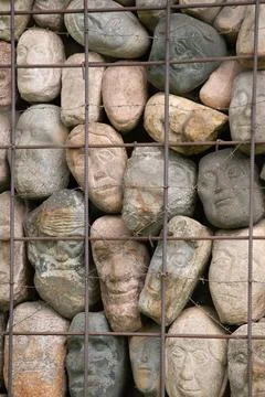 A wall of stones in the shape of human faces Stock Photos