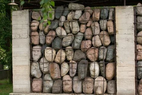 A wall of stones in the shape of human faces Stock Photos