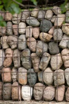 A wall of stones in the shape of human faces Stock Photos
