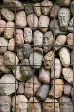 A wall of stones in the shape of human faces Stock Photos