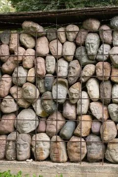 A wall of stones in the shape of human faces Stock Photos