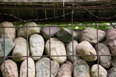 A wall of stones in the shape of human faces Stock Photos