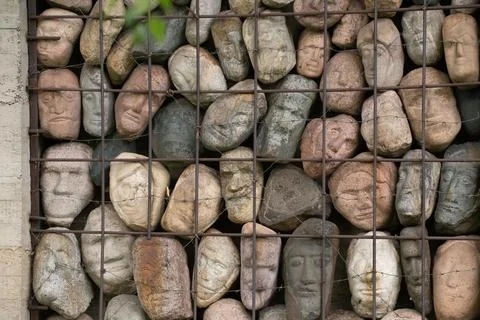 A wall of stones in the shape of human faces Stock Photos