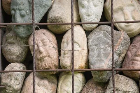 A wall of stones in the shape of human faces Stock Photos