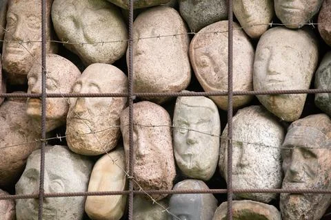 A wall of stones in the shape of human faces Stock Photos