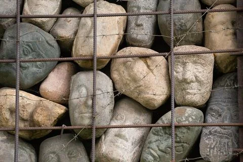 A wall of stones in the shape of human faces Stock Photos