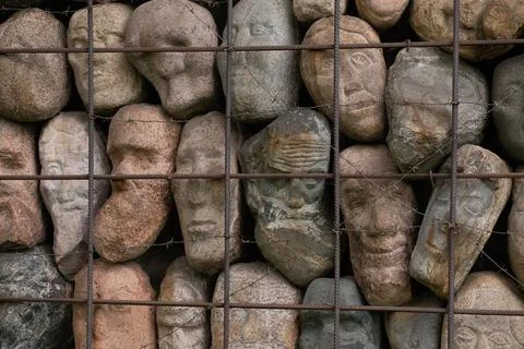 A wall of stones in the shape of human faces Stock Photos