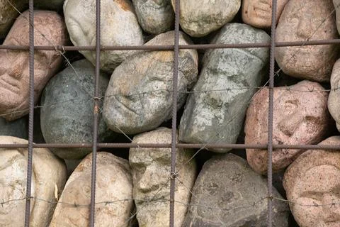 A wall of stones in the shape of human faces Stock Photos