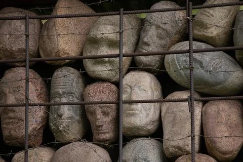 A wall of stones in the shape of human faces Stock Photos